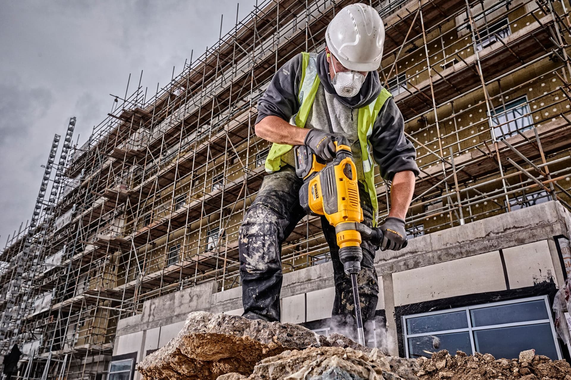 Trabajador utilizando un rotomartillo Dewalt inalámbrico en un proyecto de construcción.