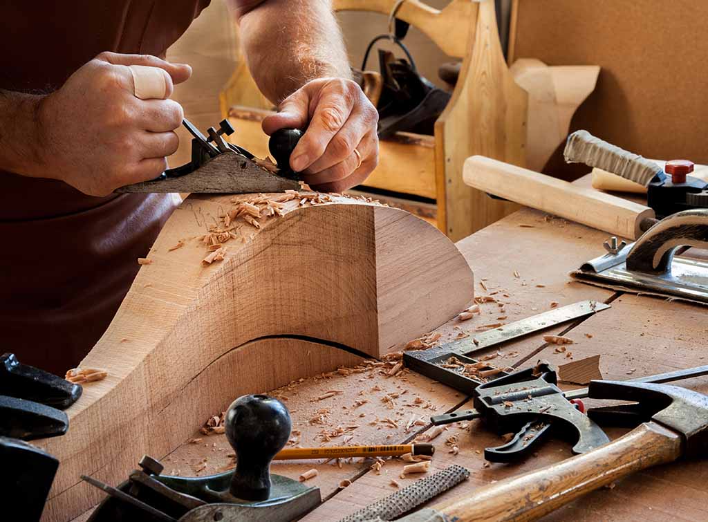 Manos utilizando una sierra eléctrica para cortar madera de forma precisa.